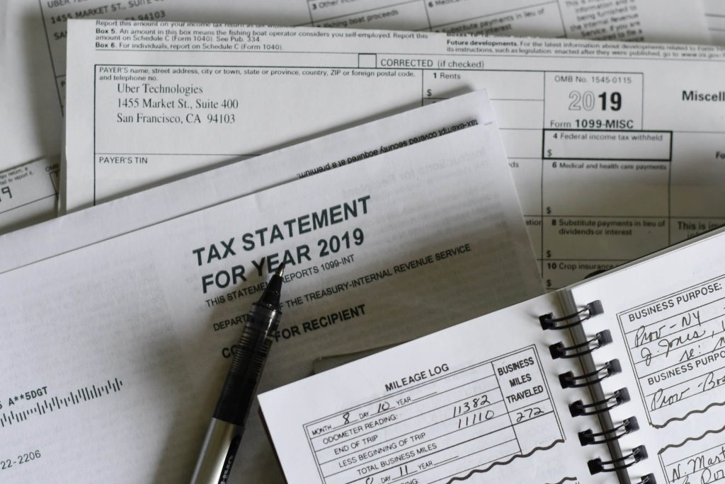 Pen resting on a tax statement and mileage log for the year 2019 with documents from Uber Technologies in San Francisco.