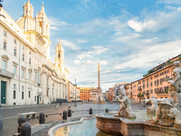 Historic square in Rome with baroque architecture, fountain, and obelisk in daylight.