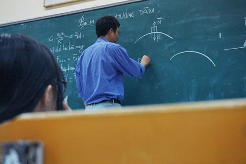 a professor is writing on a blackboard